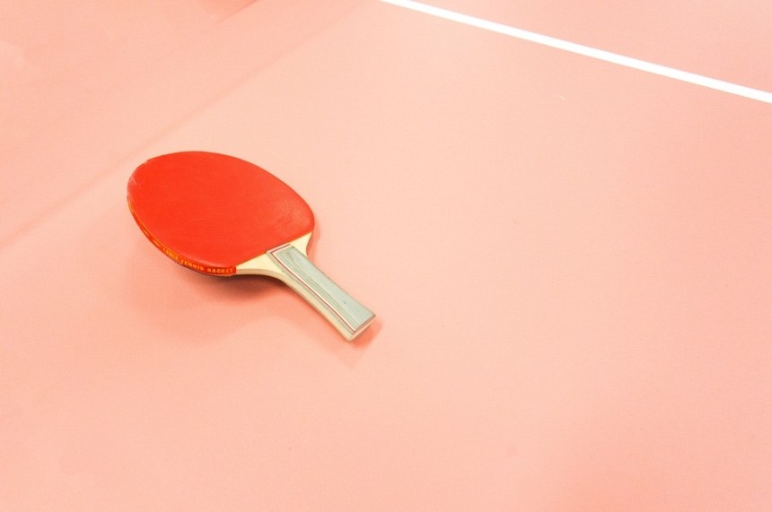 A table tennis racket on a pink background